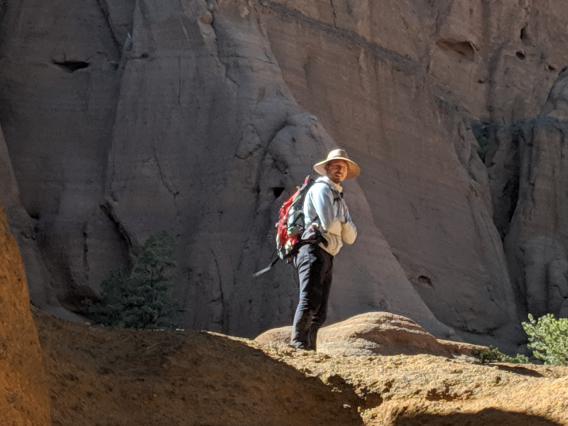 Bret standing on bare rock with a large rock wall behind him