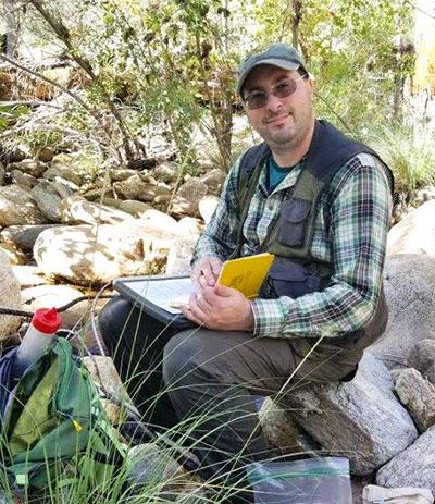 Blais taking notes by a streambed