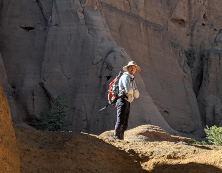 Bret standing on bare rock with a large rock wall behind him